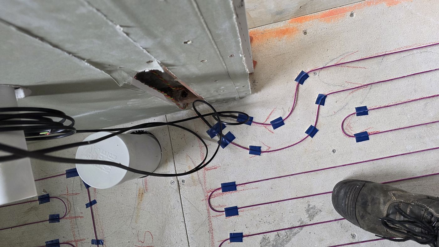 Electric underfloor heating by Floorheat NZ — the heating cable laid out across a bathroom floor before the screed goes on, the same system we fit across North Shore